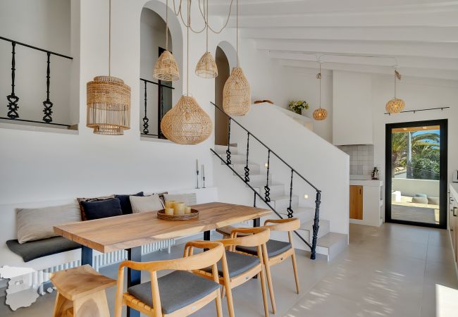 En nuestra soleada cocina, una mesa de madera emana el calor de Ibiza, rodeada de sillas y un banco acogedor.