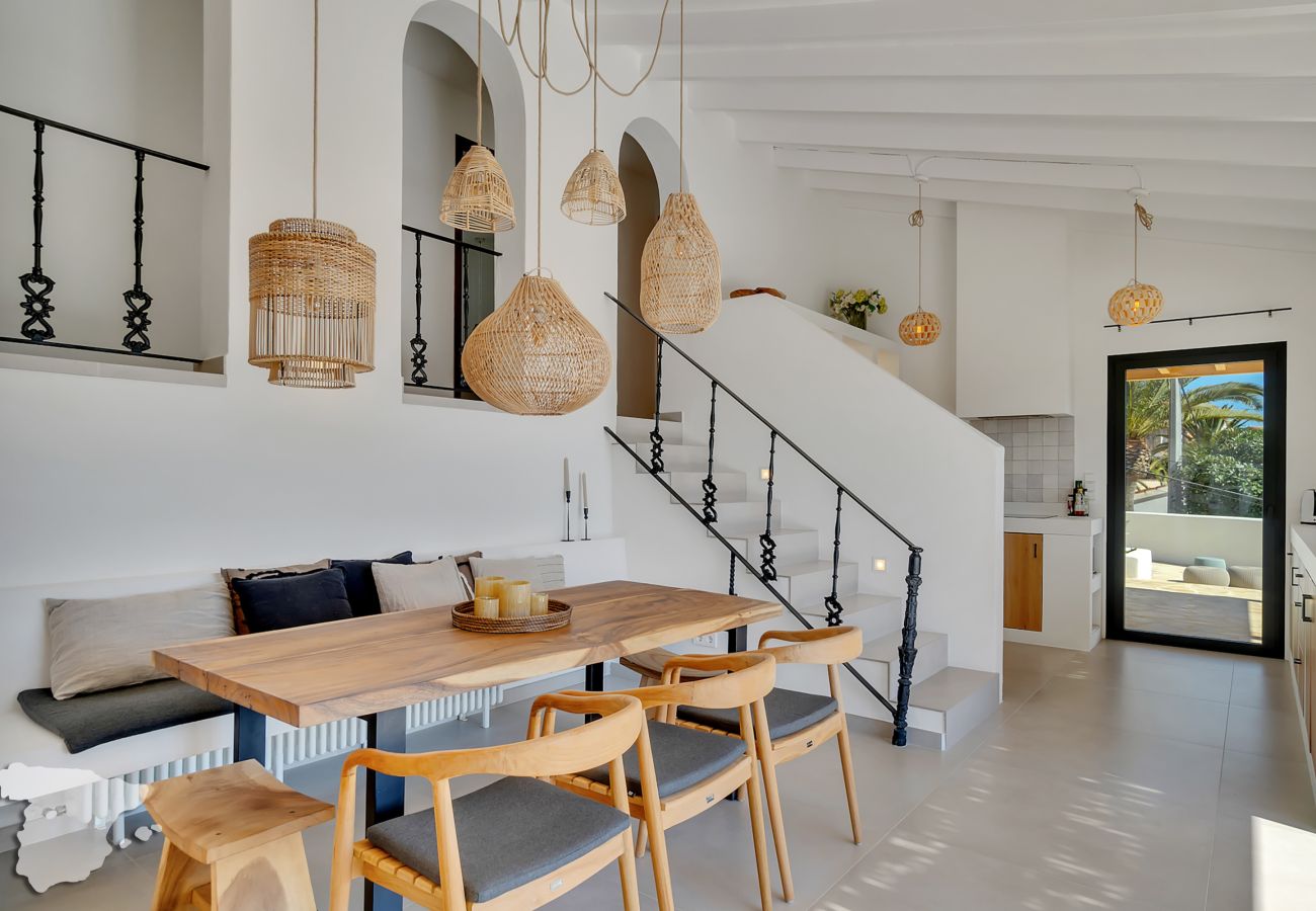 In our sunny kitchen, a wooden dining table exudes Ibiza-style warmth, surrounded by chairs and a cozy bench.